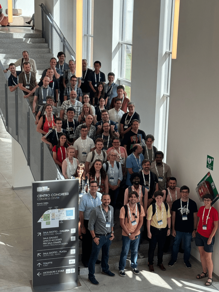 Large group photo of people at a conference, standing on stairs at a conference centre
